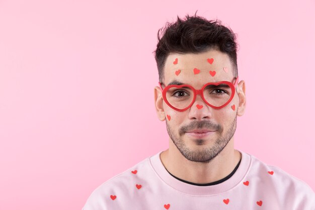 Giovane ragazzo in occhiali con cuori di carta sul viso