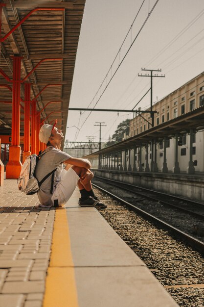 Giovane ragazzo moderno che aspetta dalla piattaforma per il treno per arrivare