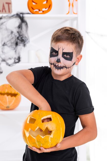 Giovane ragazzo spettrale con la zucca diabolica di Halloween