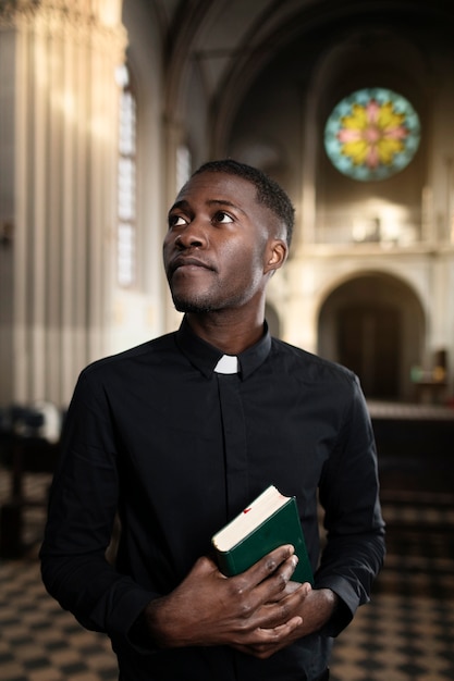 Giovane sacerdote maschio che tiene il libro sacro nella chiesa