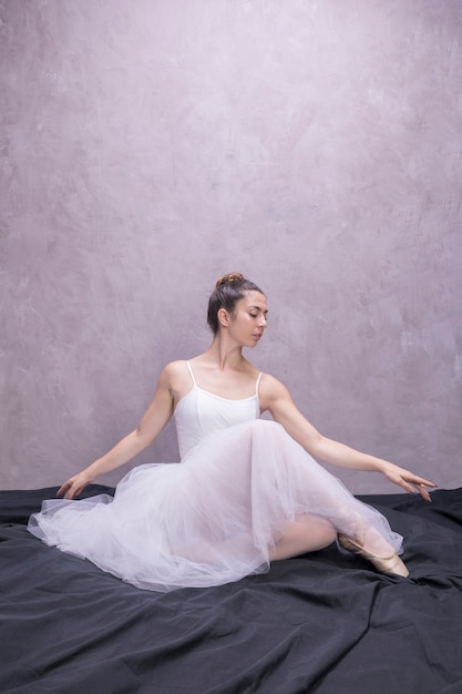 Giovane seduta della ballerina di vista frontale