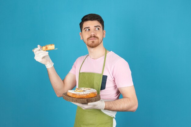 Giovane serio che tiene la fetta di torta e distoglie lo sguardo.