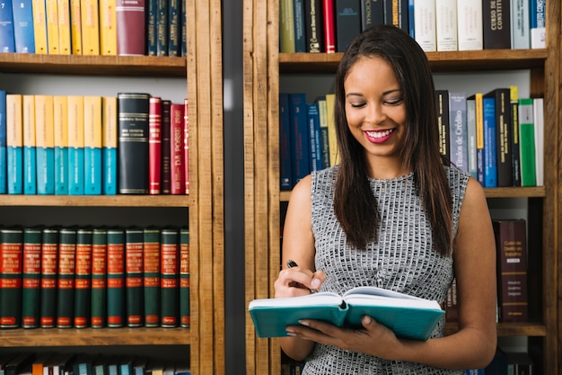 Giovane signora afroamericana sorridente con il libro