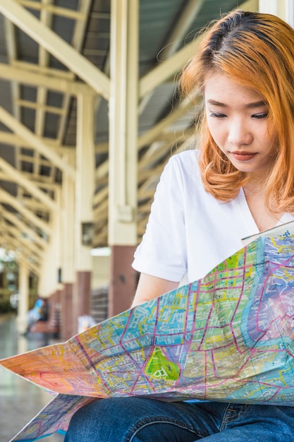 Giovane signora asiatica con mappa sulla piattaforma