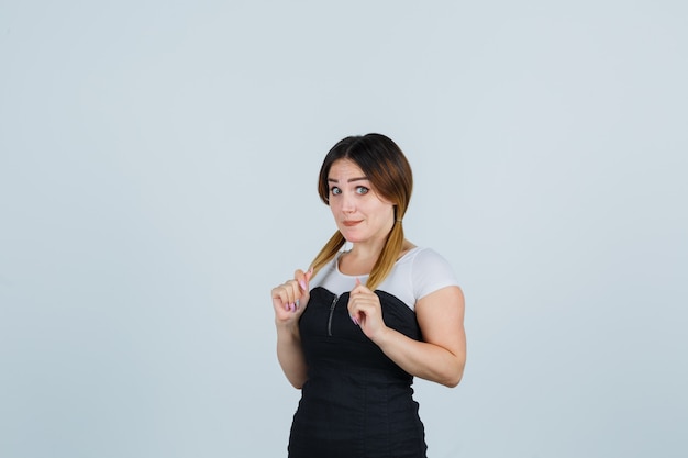 Giovane signora bionda in vestito che gesturing isolato