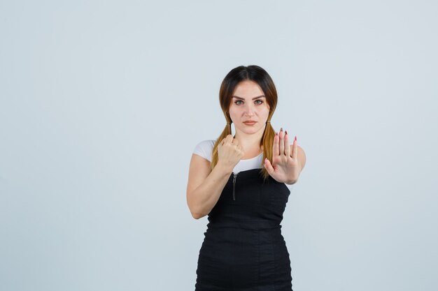 Giovane signora bionda in vestito che gesturing isolato