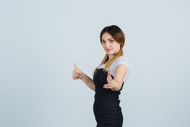 Giovane signora bionda in vestito che gesturing isolato