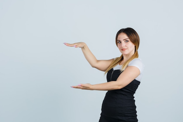 Giovane signora bionda in vestito che gesturing isolato