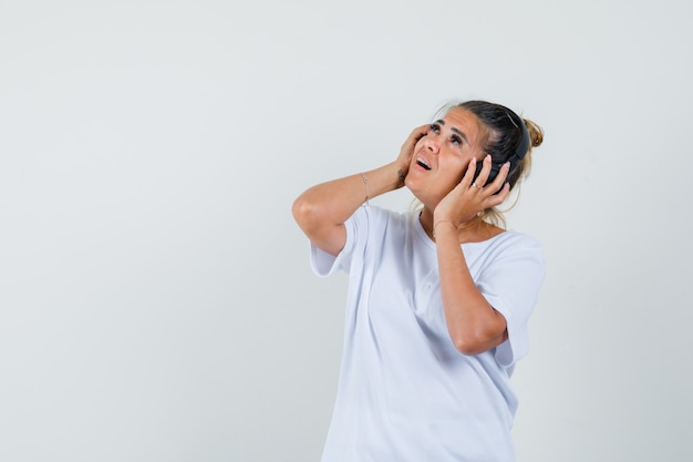 Giovane signora che ascolta la musica con le cuffie in maglietta