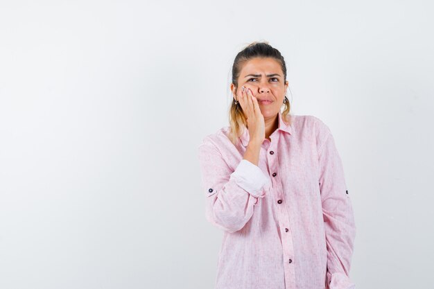 Giovane signora che tiene la mano sulla guancia in camicia rosa e che sembra eccitata