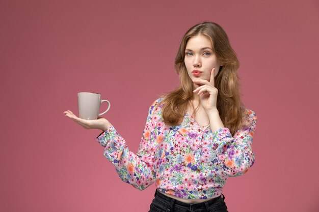 Giovane signora di vista frontale che riflette qualcosa di grande con la tazza