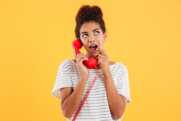 Giovane signora sorridente che giudica microtelefono rosso isolato