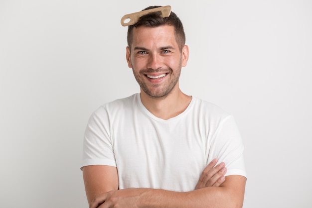 Giovane sorridente con il pettine in suoi capelli che guarda l'obbiettivo