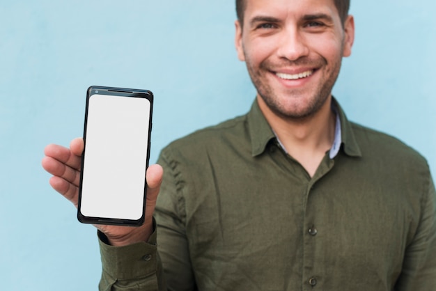 Giovane sorridente della stoppia che tiene smartphone in bianco dello schermo in bianco