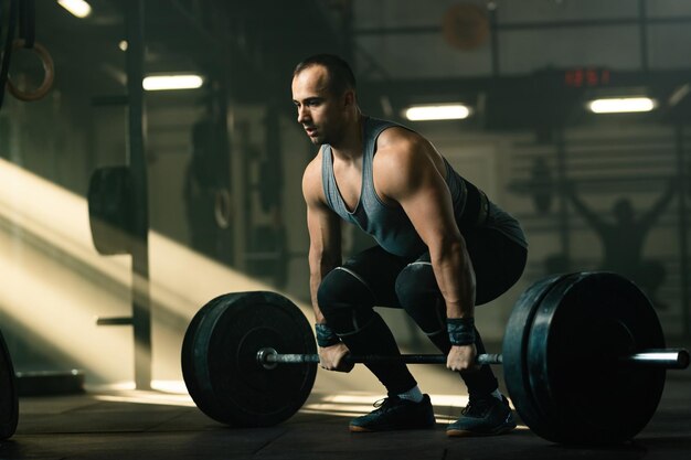 Giovane sportivo con allenamento per la forza e sollevamento del bilanciere in palestra