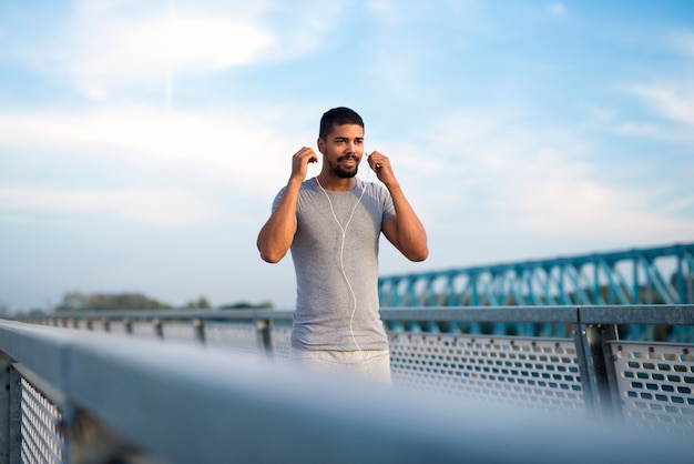 Giovane sportivo in forma che indossa gli auricolari e si concentra per l'allenamento