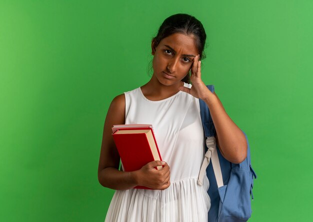 giovane studentessa che indossa uno zaino tenendo il libro con il taccuino e mettendo la mano sulla fronte