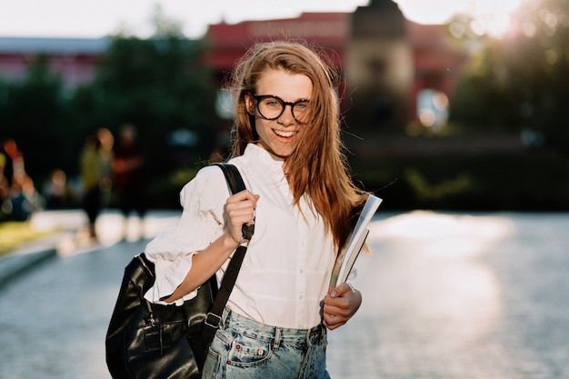 Giovane studentessa elegante adorabile indossando occhiali e camicia bianca