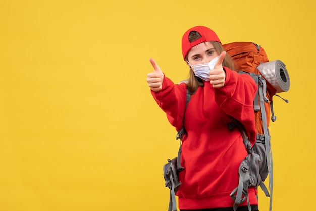 Giovane turista di vista frontale con zaino turistico e maschera che dà i pollici in su