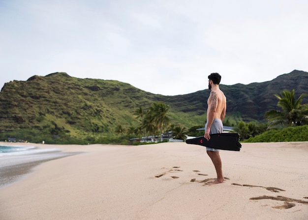 Giovane uomo a torso nudo sulla spiaggia con attrezzatura subacquea