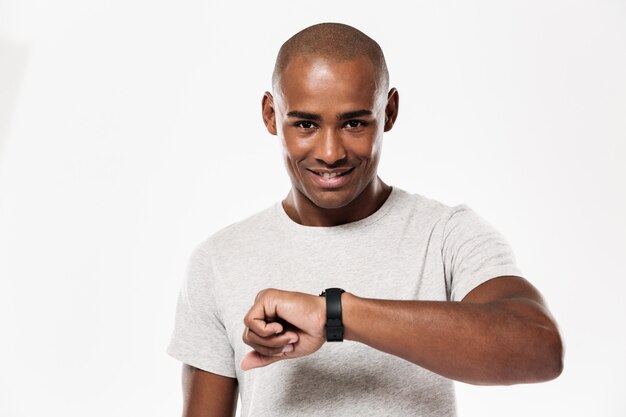 Giovane uomo africano allegro che usando orologio.