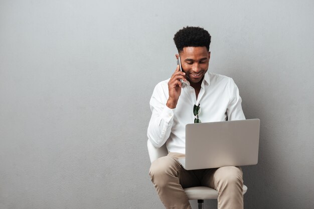 giovane uomo africano che tiene computer portatile in grembo