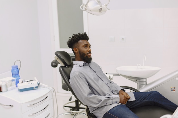Giovane uomo afro-americano. Ragazzo che visita l'ufficio del dentista per la prevenzione della cavità orale. Uomo e medico di famiglia durante il controllo dei denti.