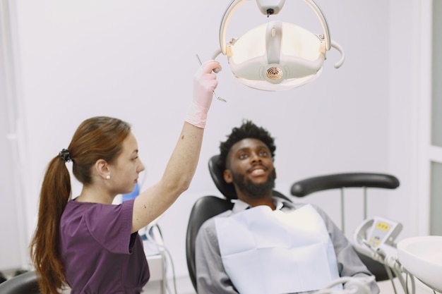 Giovane uomo afro-americano. Ragazzo che visita l'ufficio del dentista per la prevenzione della cavità orale. Uomo e medico di famiglia durante il controllo dei denti.