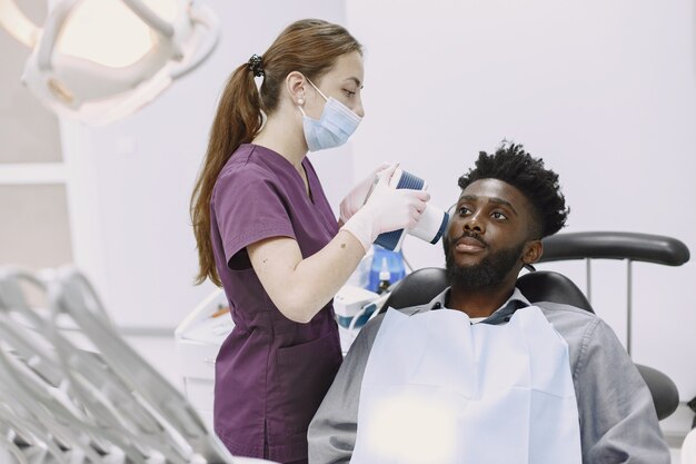 Giovane uomo afro-americano. Ragazzo che visita l'ufficio del dentista per la prevenzione della cavità orale. Uomo e medico di famiglia durante il controllo dei denti.