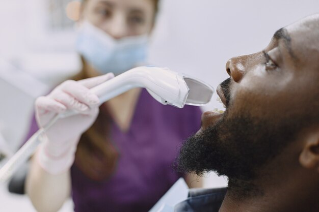 Giovane uomo afro-americano. Ragazzo che visita l'ufficio del dentista per la prevenzione della cavità orale. Uomo e medico di famiglia durante il controllo dei denti.