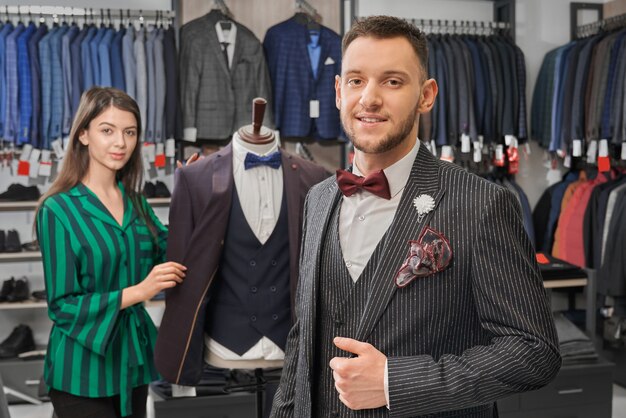 Giovane, uomo alla moda in abito elegante in posa nel negozio.