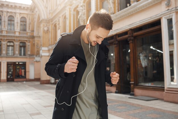 Giovane uomo allegro ballare ascoltando musica con le cuffie.