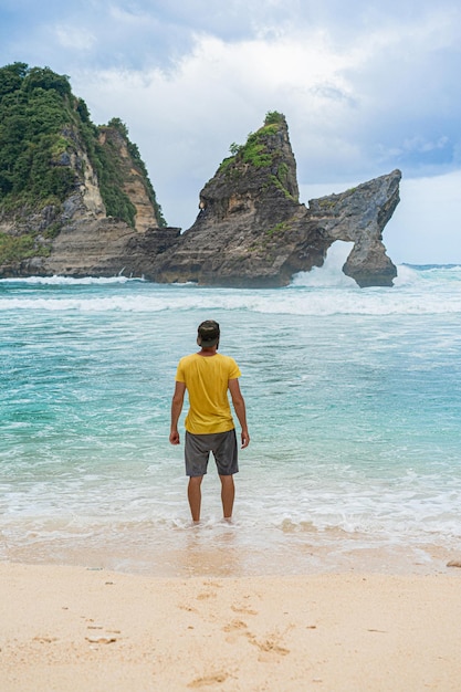 Giovane uomo barbuto bello viaggiatore dall'oceano. Spiaggia di Atuh, isola di Nusa Penida, Indonesia. Concetto di viaggio. Indonesia