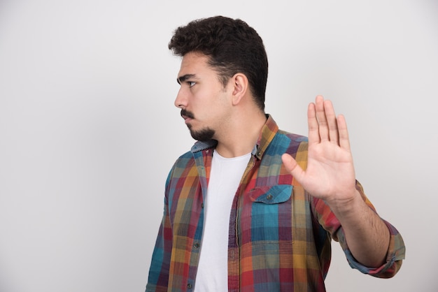 Giovane uomo barbuto che fa segno di no con la mano.