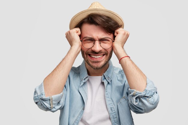 Giovane uomo barbuto con occhiali rotondi e camicia di jeans