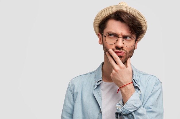 Giovane uomo barbuto con occhiali rotondi e camicia di jeans