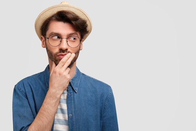 Giovane uomo barbuto con occhiali rotondi e camicia di jeans