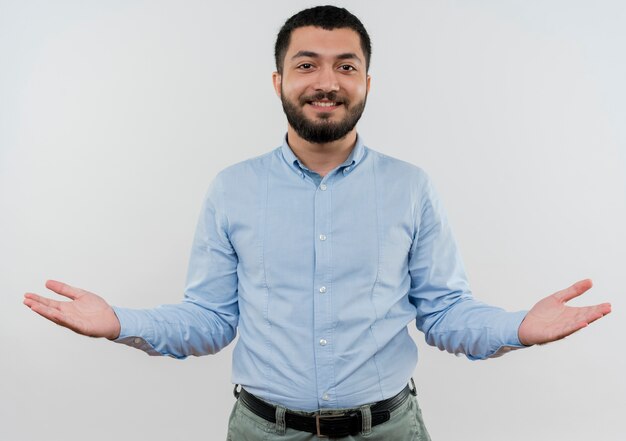 Giovane uomo barbuto in camicia blu, allargando le braccia ai lati sorridendo felice