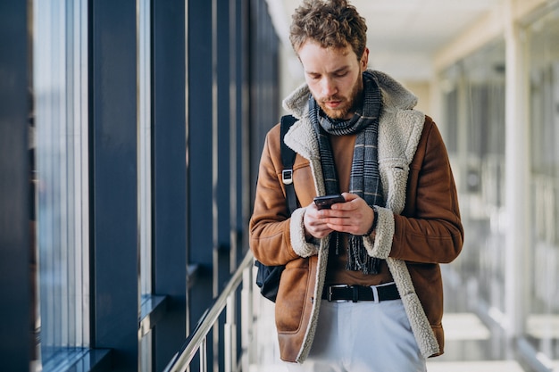 Giovane uomo bello all'aeroporto parlando al telefono