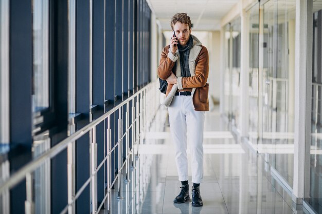 Giovane uomo bello all'aeroporto parlando al telefono