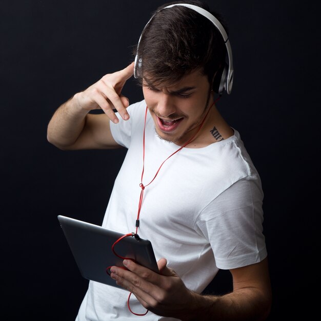 Giovane uomo bello ascoltare la musica. Isolato su nero.