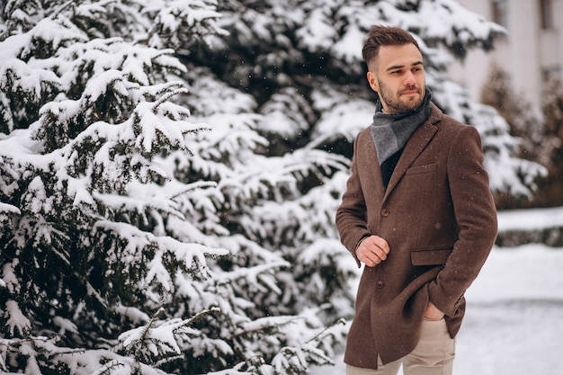 Giovane uomo bello che cammina in una foresta di inverno