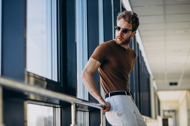 Giovane uomo bello che fa una pausa la finestra all'aeroporto