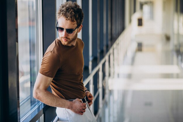 Giovane uomo bello che fa una pausa la finestra all'aeroporto