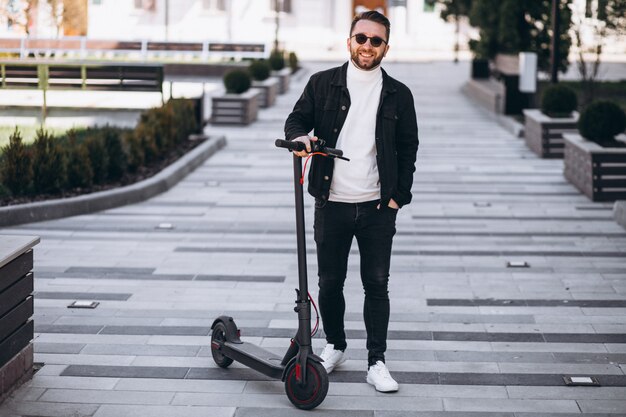 Giovane uomo bello che guida su scooter nel parco