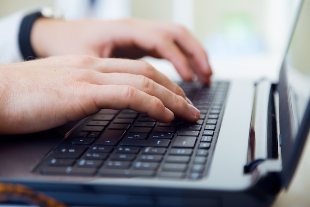 Giovane uomo bello che lavora nel suo ufficio con il computer portatile.