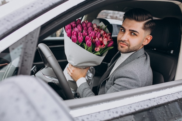 Giovane uomo bello di affari che consegna mazzo di bei fiori