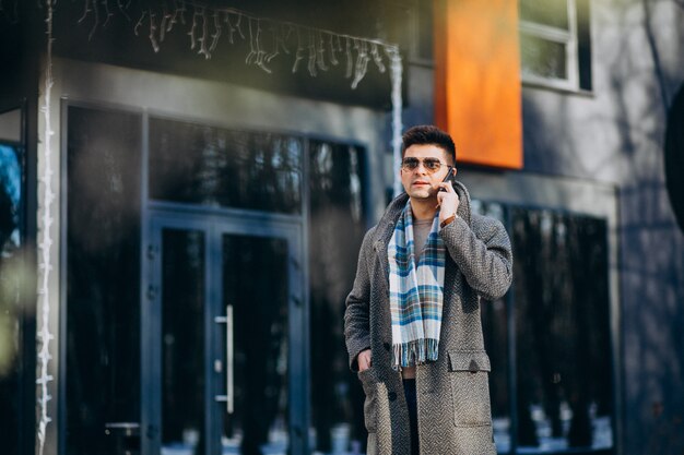 Giovane uomo bello fuori utilizzando il telefono