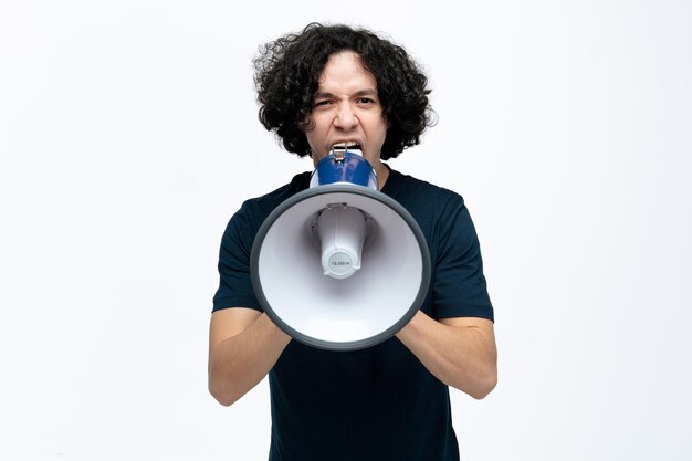 Giovane uomo bello furioso che guarda la macchina fotografica che grida ad alta voce nell'altoparlante isolato su priorità bassa bianca