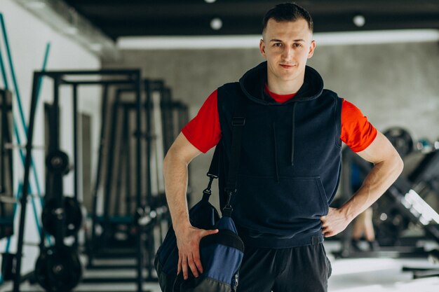 Giovane uomo bello in abiti sportivi in palestra